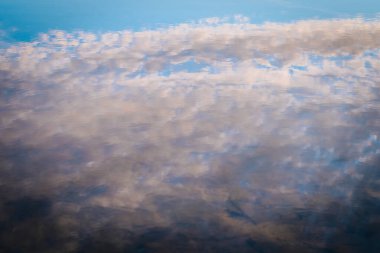 Sakin sulardaki bulutların yumuşak, bulanık bir yansıması soyut ve barışçıl bir görüntü yaratıyor. Sessiz maviler ve gri tonların karışımı sakin, rüya gibi bir atmosfer yaratır..