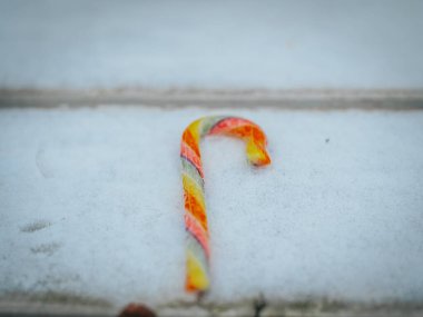 Karlı ahşap bir yüzey üzerinde duran parlak, çok renkli bir baston şeker canlı dokular ve parlak renkler sergiliyor..