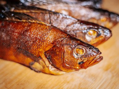 Ahşap bir yüzey üzerinde kurumuş kahverengi derili, kurutulmuş hamamböceğinin detaylı bir görüntüsü. Balığın pulları ve dokusu canlı bir şekilde vurgulanmış, kavrulmuş halini gösteriyor..