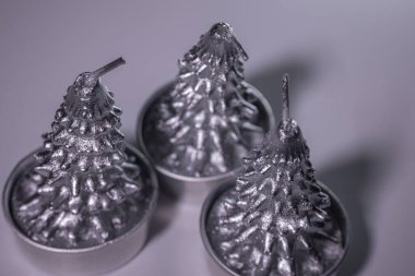  Noel ağacı şeklinde üç metalik gümüş mum yakın plan, parlak bir kapla küçük bardaklarda dizilmiş. Festival için ideal..