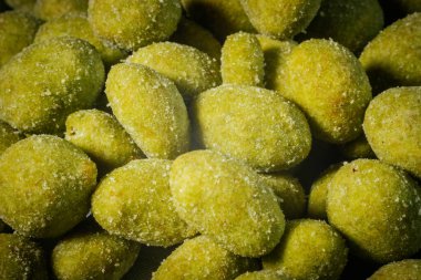 İnce bir toz ile kaplanmış parlak sarı-yeşil wasabi tadında fındıklar, baharatlı ve çıtır çıtır bir aperatif oluşturuyor. Vurgu için bulanık arkaplan.