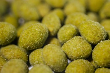 İnce bir toz ile kaplanmış parlak sarı-yeşil wasabi tadında fındıklar, baharatlı ve çıtır çıtır bir aperatif oluşturuyor. Vurgu için bulanık arkaplan.