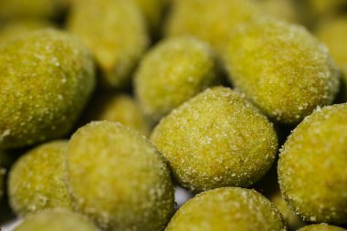 İnce bir toz ile kaplanmış parlak sarı-yeşil wasabi tadında fındıklar, baharatlı ve çıtır çıtır bir aperatif oluşturuyor. Vurgu için bulanık arkaplan.