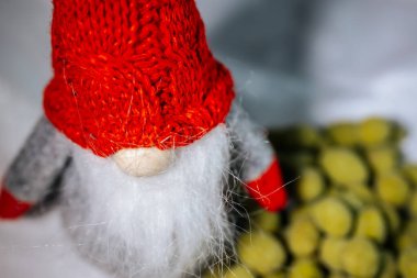 Süslü kırmızı şapkalı, beyaz sakallı, arka planı bulanık, wasabi aromalı sarı yeşil fındıklı bir cücenin yakın çekimi. Tatil temaları ve mevsimlik tasarımlar için ideal.