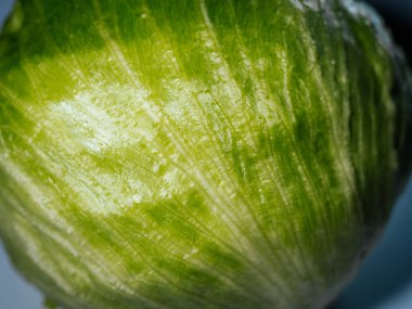 Parlak yeşil yaprakları ve taze bir dokusu olan ve doğal tazeliğini vurgulayan bir buzdağı marulu kafasının yakın plan çekimi..