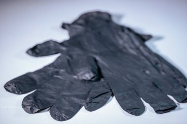 Açık bir yüzeye yerleştirilmiş iki adet tek kullanımlık siyah nitril eldiven. Yumuşak dokusu ve eldivenlerin ayrıntıları açıkça görülüyor..