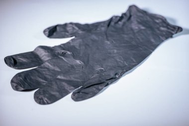 Açık bir yüzeye yerleştirilmiş iki adet tek kullanımlık siyah nitril eldiven. Yumuşak dokusu ve eldivenlerin ayrıntıları açıkça görülüyor..