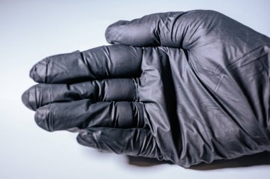Siyah, eski bir eldiven giyen, arka planda hafif bir el. Eldivenin dokusu ve ayrıntıları açıkça görülüyor..