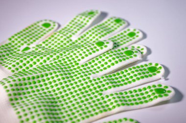 A close-up view of several white gloves with green dotted fingers for improved functionality. The gloves are arranged overlapping on a white background. clipart