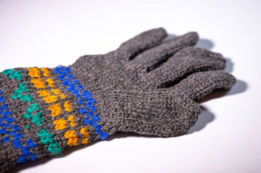 Mavi, sarı ve yeşil renkli parlak dekoratif desenli gri örgü eldivenler. Eldivenler beyaz arka plana yerleştiriliyor..