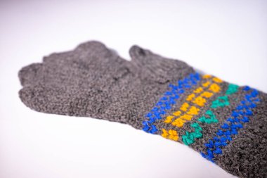 Mavi, sarı ve yeşil renkli parlak dekoratif desenli gri örgü eldivenler. Eldivenler beyaz arka plana yerleştiriliyor..