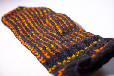 Parlak turuncu ve sarı çizgili siyah örülmüş kumaşın detaylı bir görüntüsü. Dokuma malzemesi beyaz bir arka plana yerleştiriliyor..