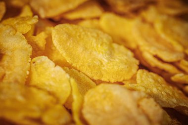 Çıtır çıtır ve parlak sarı renkli altın mısır gevreğinin detaylı bir makro çekimi, doğal cazibelerini vurguluyor..