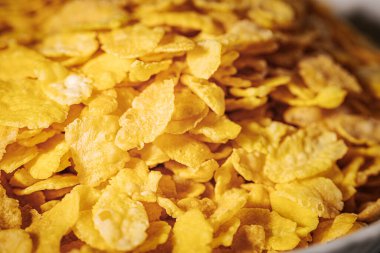 Altın mısır gevreğiyle dolu beyaz bir kase gevrek dokusunu ve parlak sarı rengini gözler önüne seriyor..