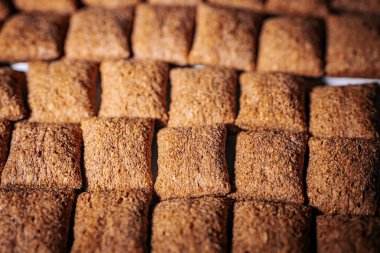 Kahverengi mısır gevreği karelerinin düzenli bir şekilde sıralanması, çıtır çıtır dokularını ve sağlıklı görünümlerini vurguluyor..