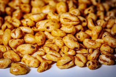 Beyaz arkaplana saçılmış altın kabarık mısır gevrekleri kopyası için bolca yer bırakıyor. Balla kaplanmış dokusu ışıkta parlıyor, çıtırtısını vurguluyor..