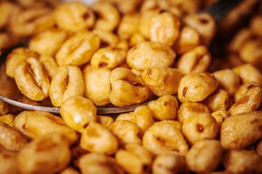 Bir kaşık yakın plan, altın renkli mısır gevreği parçaları, parlak bal kaplamalı, çıtır çıtır ve iştah açıcı görünümlerini vurgulayan..