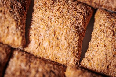 Kahverengi mısır gevreği karelerinin düzenli bir şekilde sıralanması, çıtır çıtır dokularını ve sağlıklı görünümlerini vurguluyor..