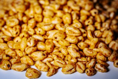 Beyaz arkaplana saçılmış altın kabarık mısır gevrekleri kopyası için bolca yer bırakıyor. Balla kaplanmış dokusu ışıkta parlıyor, çıtırtısını vurguluyor..