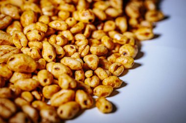 Beyaz arkaplana saçılmış altın kabarık mısır gevrekleri kopyası için bolca yer bırakıyor. Balla kaplanmış dokusu ışıkta parlıyor, çıtırtısını vurguluyor..