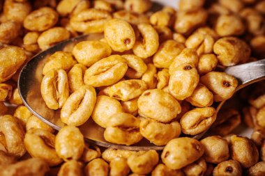 Bir kaşık yakın plan, altın renkli mısır gevreği parçaları, parlak bal kaplamalı, çıtır çıtır ve iştah açıcı görünümlerini vurgulayan..