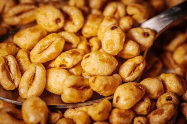 Bir kaşık yakın plan, altın renkli mısır gevreği parçaları, parlak bal kaplamalı, çıtır çıtır ve iştah açıcı görünümlerini vurgulayan..