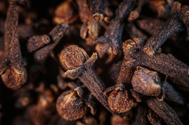 Kurumuş karanfillerin aşırı yakın çekimi, dokularının ve yapılarının karmaşık detaylarını gösteriyor. Zengin kahverengi tonlar sıcak ışıkla vurgulanır..