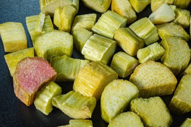 Dondurulmuş, kurutulmuş, yeşil ve pembe tonlarını detaylı dokularla gösteren rubarb parçaları. Çıtır çıtır ve doğal bir atıştırmalık için saklandı..