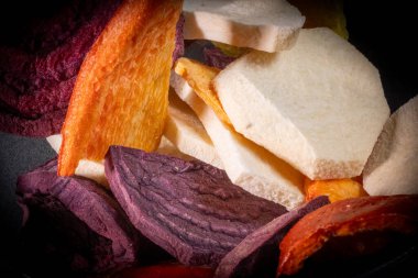 Renkli sebze dilimleri ve havuç, mor tatlı patates ve diğer parlak parçaları içeren meyveler..