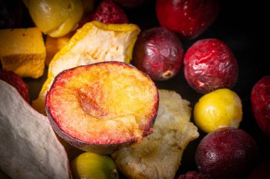 Kuru erik, kızılcık ve balkabağı parçaları da dahil olmak üzere çeşitli kurumuş meyvelerin yakın plan çekimlerinde canlı renkleri ve dokuları vurgulanıyor..