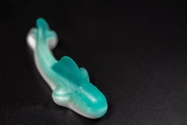 Siyah arkaplandaki mavi ve beyaz şekerleme yığınının yakın çekimi. Şekerlerin parlak, şeffaf bir dokusu ve yumuşak, çiğnenebilir bir görüntüsü var..