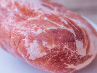 Beyaz bir tabağa konmuş taze, çiğ domuz pirzolası. Zengin doku ve doğal renk etin kalitesini vurgular, pişirilmeye hazır..