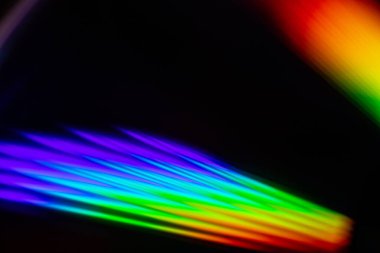 Parlak gökkuşağı yansımalı bir CD 'nin yakın çekimi. Dinamik bulanık etki, karanlık bir arka plana karşı soyut ve fütüristik hissi artırır..