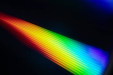 Parlak gökkuşağı yansımalı bir CD 'nin yakın çekimi. Dinamik bulanık etki, karanlık bir arka plana karşı soyut ve fütüristik hissi artırır..