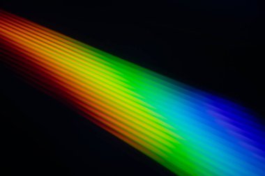 Parlak gökkuşağı yansımalı bir CD 'nin yakın çekimi. Dinamik bulanık etki, karanlık bir arka plana karşı soyut ve fütüristik hissi artırır..