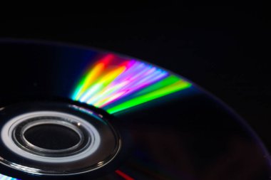 Parlak gökkuşağı yansımalı bir CD 'nin yakın çekimi. Dinamik bulanık etki, karanlık bir arka plana karşı soyut ve fütüristik hissi artırır..