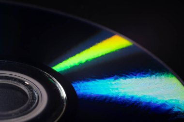 Parlak gökkuşağı yansımalı bir CD 'nin yakın çekimi. Dinamik bulanık etki, karanlık bir arka plana karşı soyut ve fütüristik hissi artırır..