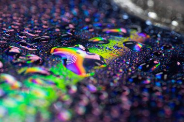 Göz kamaştırıcı renkli bir gökkuşağını yansıtan bir CD 'de su damlacıklarının makro görüntüsü. Işığın kırılması, zengin dokular ve canlı renklerle büyüleyici bir soyut etki yaratır..