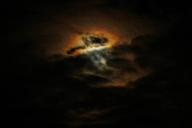 Koyu bulutlu loş bir gökyüzü turuncu ve mavinin hafif yanardöner tonlarını ortaya çıkararak ürkütücü, göksel bir ışıltıyla karamsar ve atmosferik bir sahne yaratıyor..