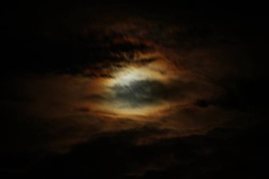 Koyu bulutlu loş bir gökyüzü turuncu ve mavinin hafif yanardöner tonlarını ortaya çıkararak ürkütücü, göksel bir ışıltıyla karamsar ve atmosferik bir sahne yaratıyor..