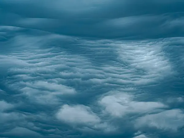  Yoğun, katmanlı mavi fırtına bulutları gökyüzünde dalgalanan dokular oluşturur. Bir ışık demeti yavaşça kırılır. Kompozisyon kopyalama alanını içeriyor.