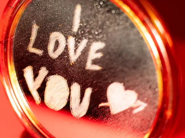 Parlak ışık ve sığ odak ile yakalanmış, sisli bir aynaya çizilmiş bir kalp ile romantik bir 