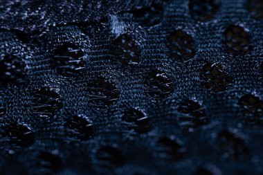 Dairesel örgü desenli siyah bir örgü kumaşın yakın çekimi, dokuyu, dokuyu ve nefes alabilirliği vurguluyor. Tekstil ve tasarım referansları için ideal.