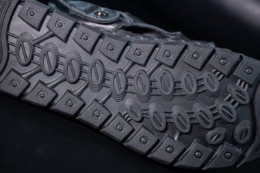 Kauçuk ayakkabı tabanının detaylı bir makro görüntüsü oval lastik desenleri ve koyu mavi tonda vida benzeri şekilleri gösteriyor..