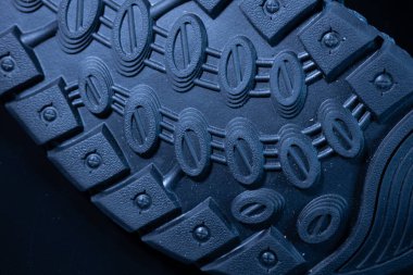 Kauçuk ayakkabı tabanının detaylı bir makro görüntüsü oval lastik desenleri ve koyu mavi tonda vida benzeri şekilleri gösteriyor..