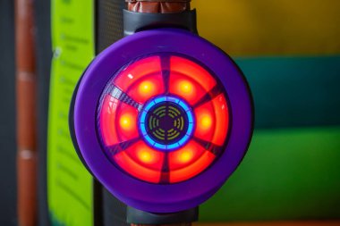 Kırmızı, mavi ve sarı LED 'leri olan canlı, dairesel etkileşimli bir ışık hedefi, kapalı bir oyun alanındaki bir yapıya monte edilmiş, parlak bir şekilde parlıyor..