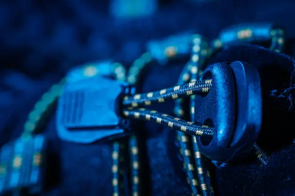  Siyah atletik bir ayakkabının üzerinde, hızlı ayarlama için sarı çizgili ipler ve plastik bağlayıcıların yer aldığı kauçuk stili elastik bağlama sisteminin ayrıntılı görünümü.