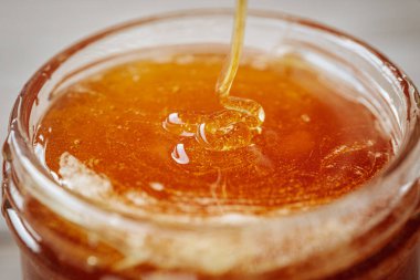 Cam bir kavanoza doldurulan kalın altın bal, zengin dokusunu ve doğal parıltısını ön plana çıkarıyor..