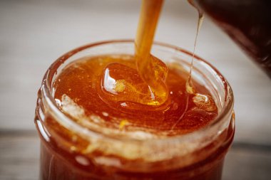 Cam bir kavanoza doldurulan kalın altın bal, zengin dokusunu ve doğal parıltısını ön plana çıkarıyor..