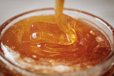 Cam bir kavanoza doldurulan kalın altın bal, zengin dokusunu ve doğal parıltısını ön plana çıkarıyor..